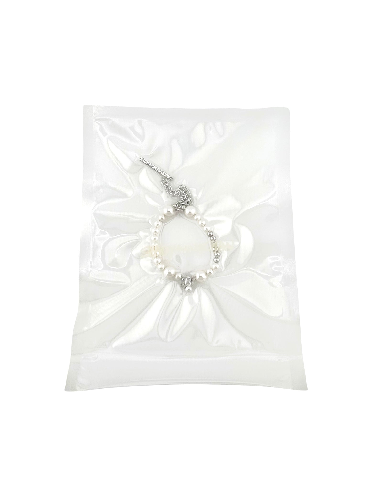 A silver and pearl bracelet in a clear plastic packaging.