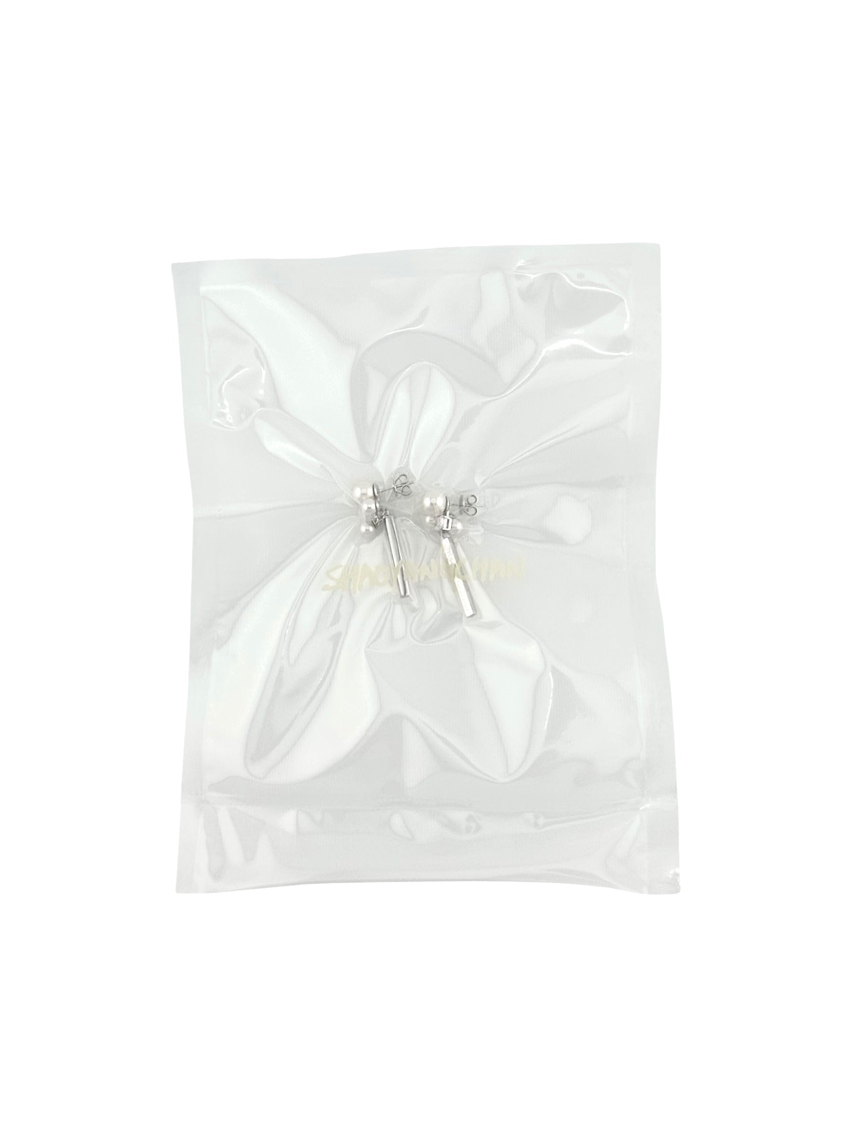 A pair of silver and pearl earrings in an anti-tarnish plastic packaging.