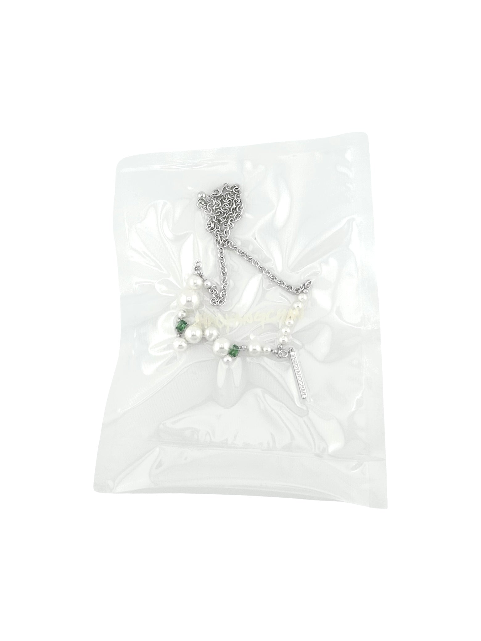 A necklace packaged in a clear plastic bag, featuring a silver chain with Pearls.